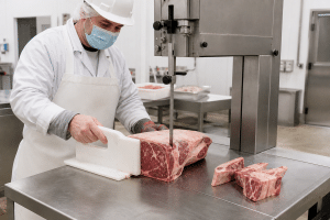 Commercial meat band saw set up for controlled cutting of bone-in meat