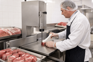 Commercial meat band saw set up for consistent portion cutting in a clean butcher workstation